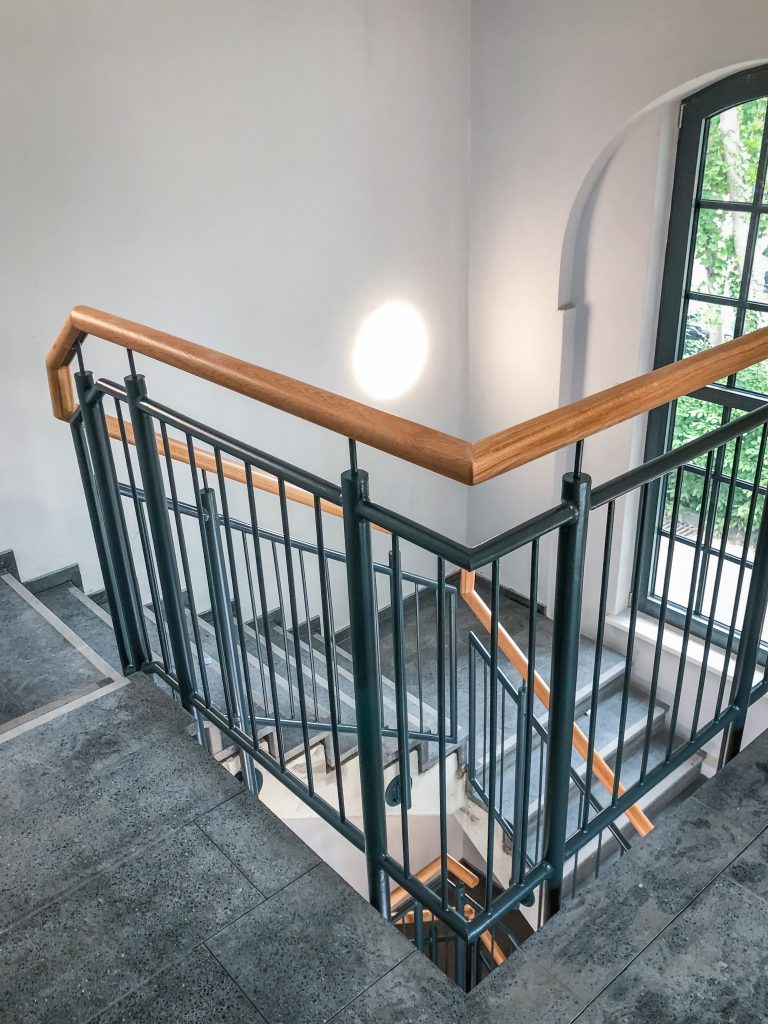 Modernes Treppenhaus mit neu gestaltetem Metallgeländer und Holzhandlauf