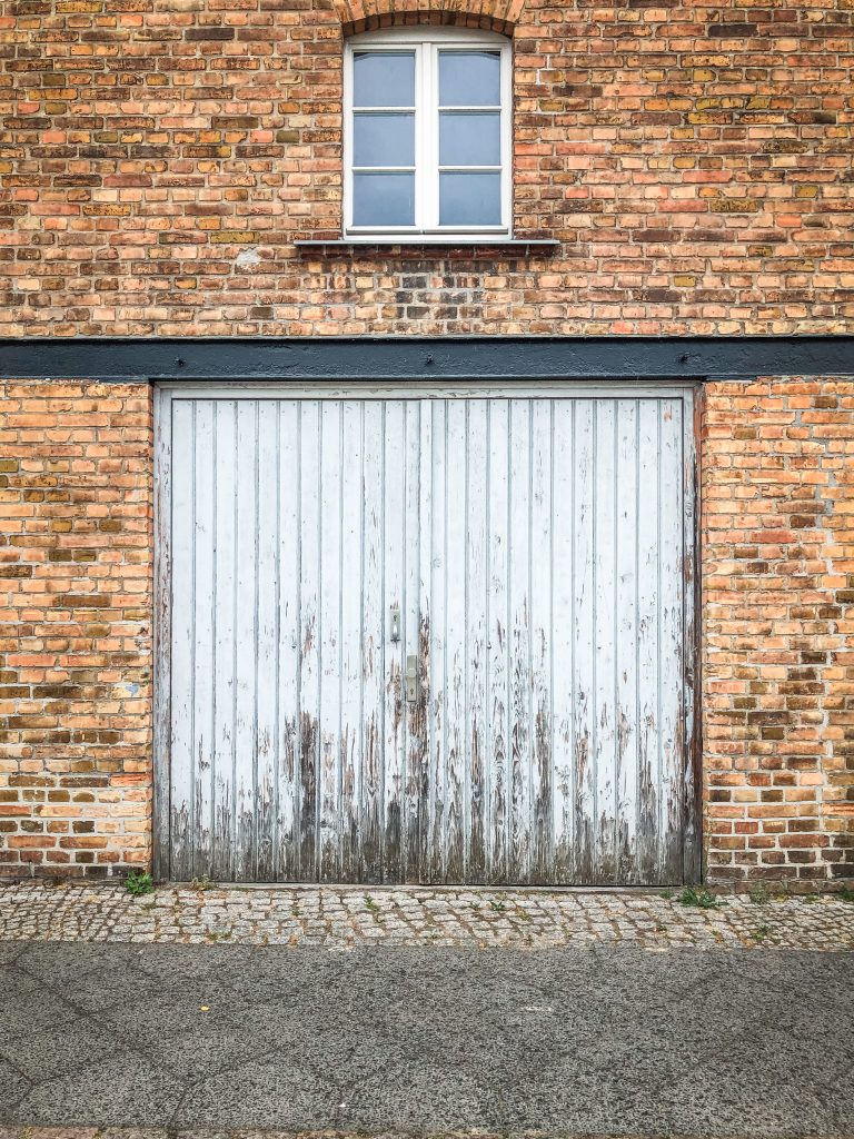 Alte Garagentür aus Holz an einer Backsteinfassade vor der Renovierung