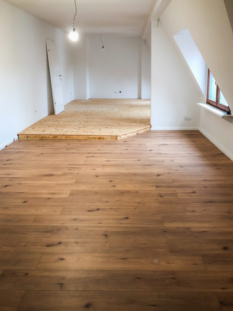 Renovierter Dachgeschossraum mit hellem Wandanstrich und aufgearbeitetem Holzboden